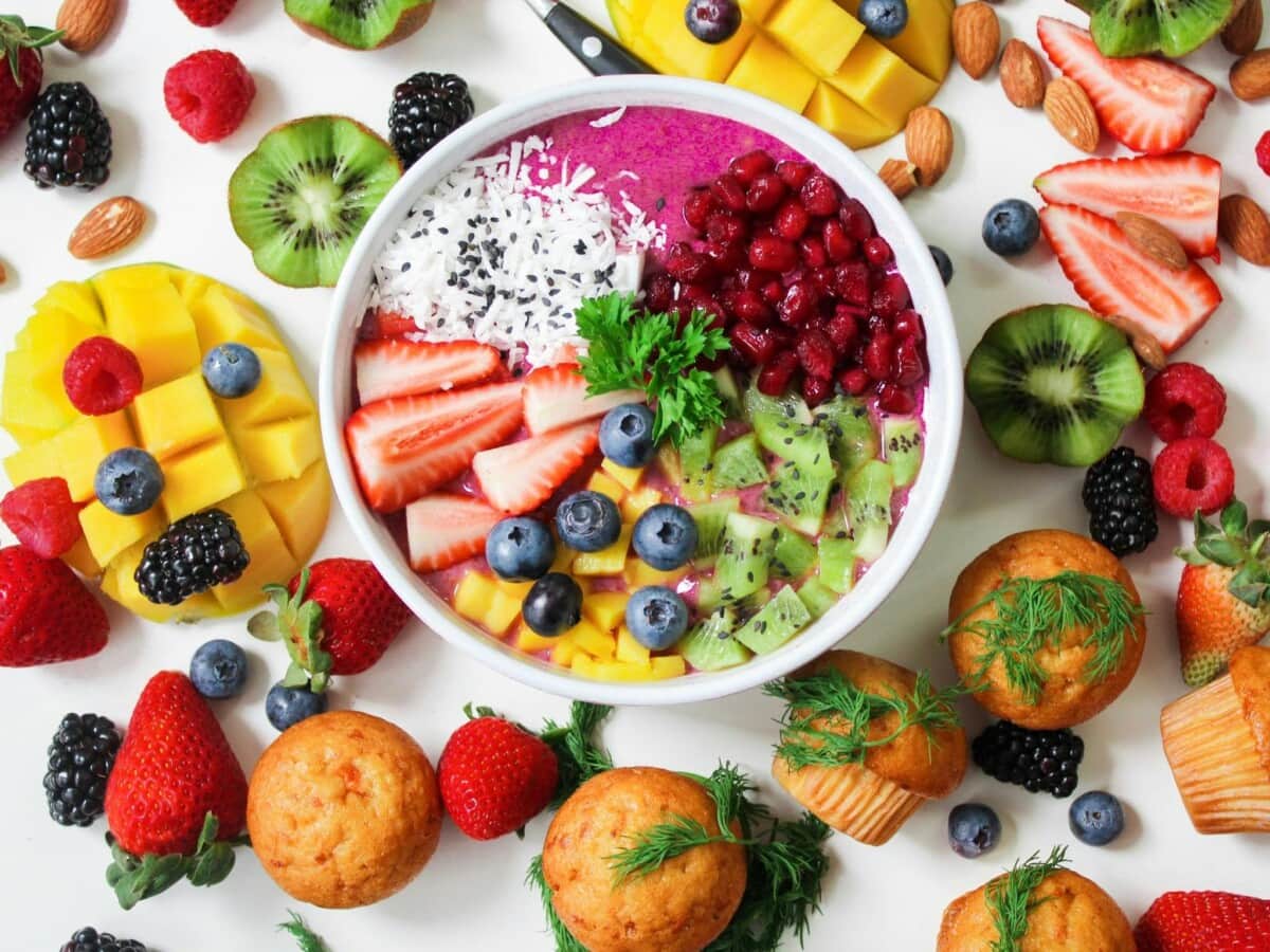 Assorted fruits and muffins surrounding filled bowl