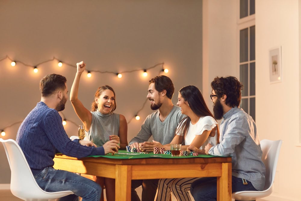 Friends playing poker together, as one friend cheers